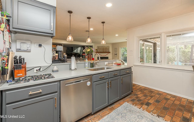 kitchen featuring appliances with stainless steel finishes, gray cabinets, a sink, and a peninsula