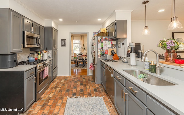 kitchen featuring appliances with stainless steel finishes, gray cabinets, brick floor, and a sink