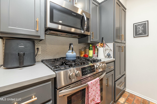 kitchen featuring stainless steel appliances, backsplash, light countertops, and gray cabinetry