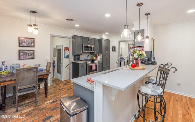 kitchen featuring a breakfast bar, light countertops, visible vents, appliances with stainless steel finishes, and a sink