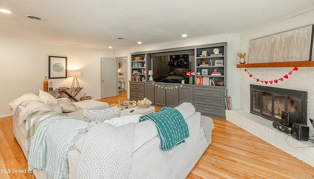 living room with visible vents, a brick fireplace, light wood-style flooring, and recessed lighting