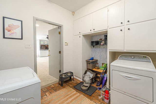 laundry room with brick floor, cabinet space, washing machine and dryer, and carpet