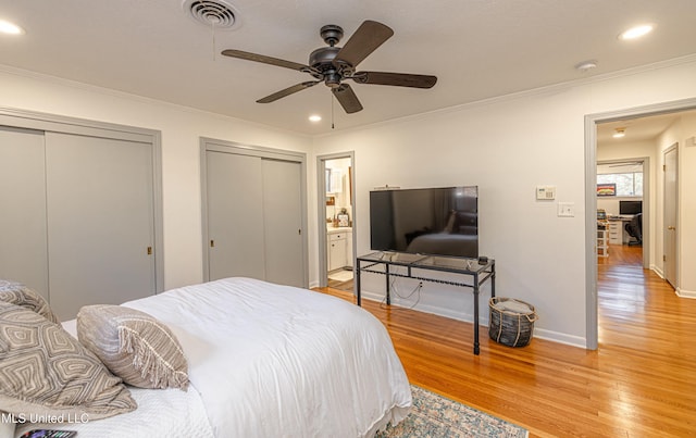 bedroom with visible vents, crown molding, light wood-style floors, two closets, and recessed lighting