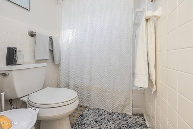 bathroom with toilet, a shower with shower curtain, and tile walls