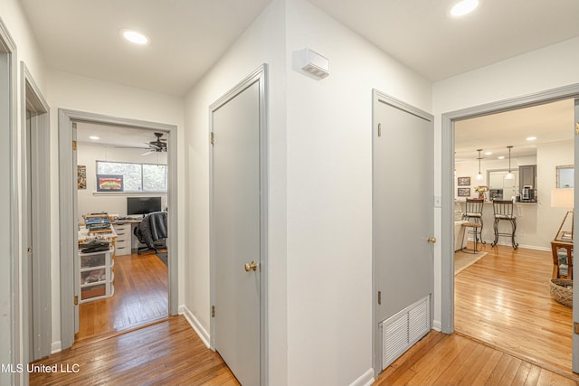 corridor featuring baseboards, light wood-style flooring, visible vents, and recessed lighting