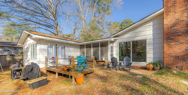 exterior space featuring brick siding, a wooden deck, and a sunroom