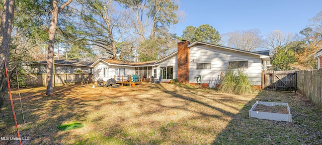 back of house featuring a lawn, a chimney, a vegetable garden, and a fenced backyard