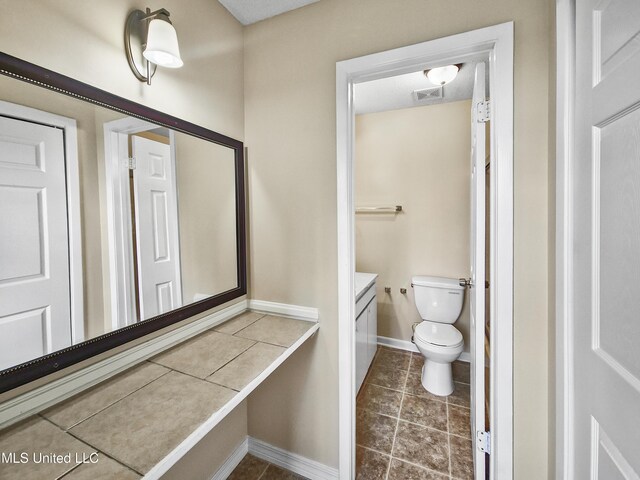 bathroom featuring visible vents, tile patterned flooring, vanity, baseboards, and toilet