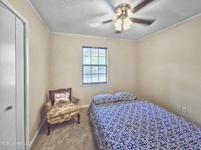 carpeted bedroom featuring baseboards, ornamental molding, a ceiling fan, and a textured ceiling