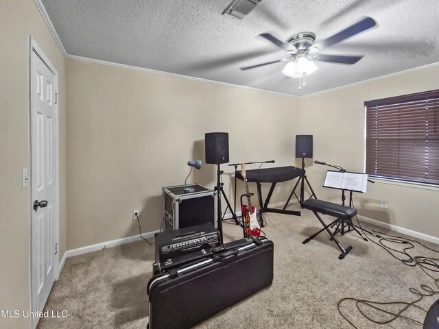 exercise area featuring carpet flooring, a textured ceiling, a ceiling fan, baseboards, and ornamental molding