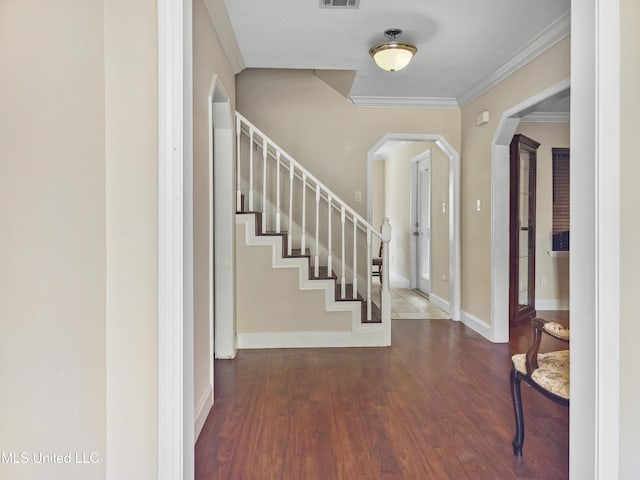 foyer with crown molding, arched walkways, wood finished floors, and visible vents