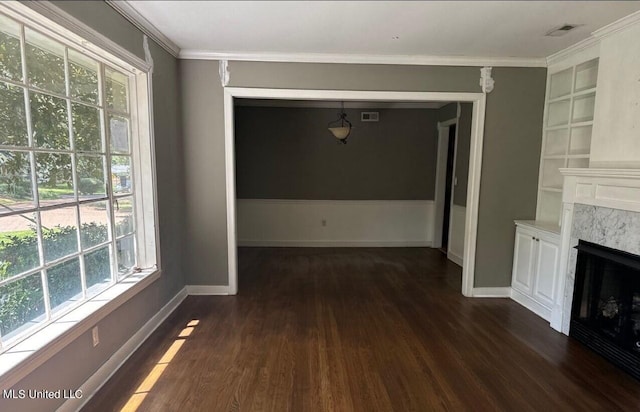 unfurnished living room featuring crown molding, built in features, a wealth of natural light, and dark hardwood / wood-style floors