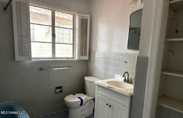 bathroom featuring toilet, a healthy amount of sunlight, vanity, and tile walls