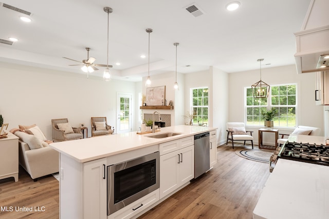 kitchen featuring a kitchen island with sink, sink, white cabinets, and appliances with stainless steel finishes