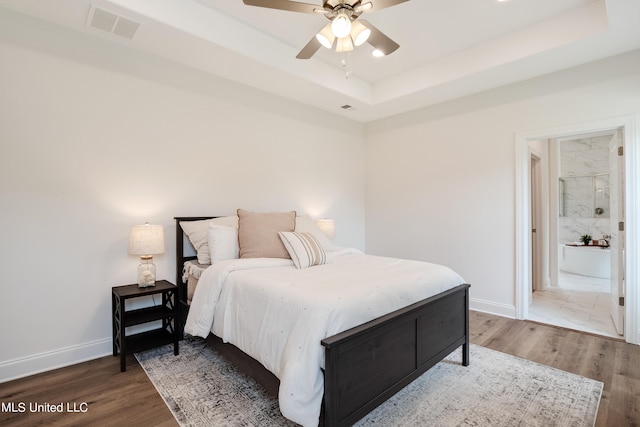 bedroom with a raised ceiling, ceiling fan, and hardwood / wood-style floors