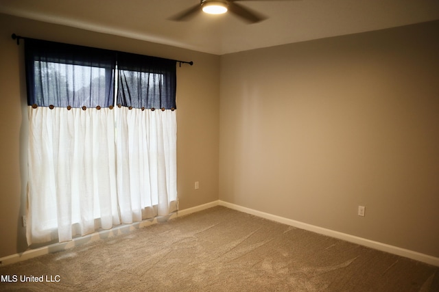 carpeted spare room with a ceiling fan and baseboards