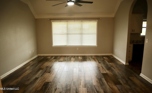 spare room with a ceiling fan, crown molding, arched walkways, dark wood-type flooring, and baseboards