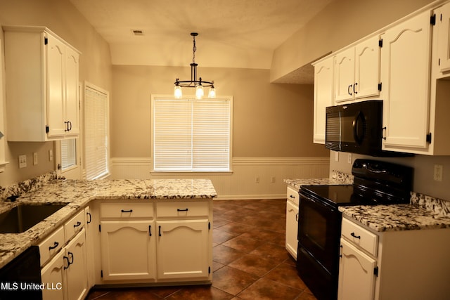 kitchen with black appliances, a peninsula, white cabinetry, light stone countertops, and a wainscoted wall