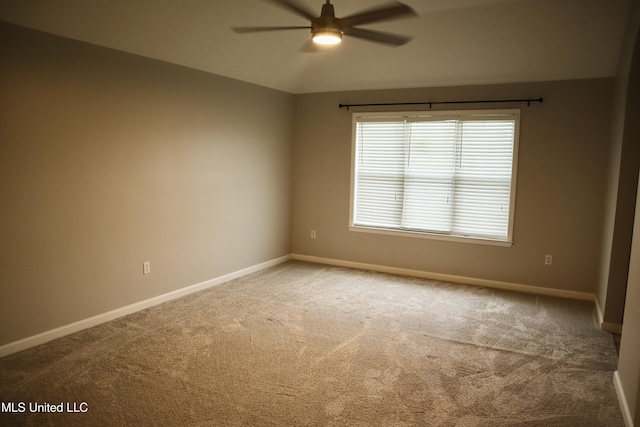 carpeted spare room with a ceiling fan and baseboards