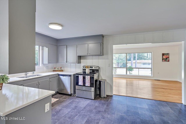 kitchen featuring gray cabinetry, sink, appliances with stainless steel finishes, dark hardwood / wood-style flooring, and kitchen peninsula