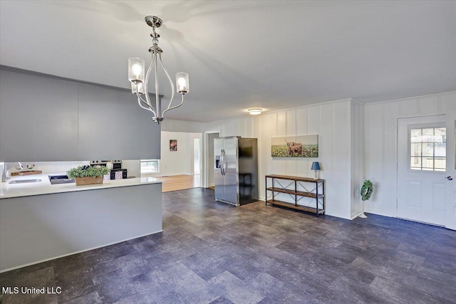 kitchen featuring stainless steel refrigerator with ice dispenser, ornamental molding, sink, pendant lighting, and an inviting chandelier