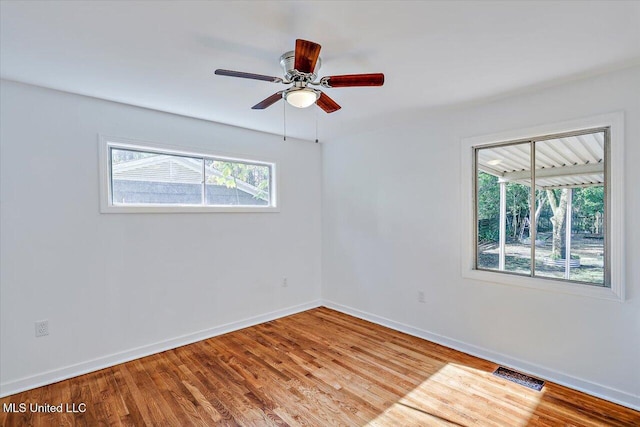 empty room featuring hardwood / wood-style floors, ceiling fan, and a healthy amount of sunlight