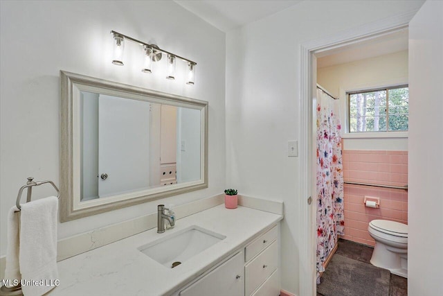 bathroom featuring vanity, tile walls, and toilet