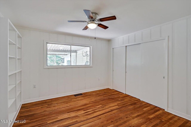 unfurnished bedroom featuring ceiling fan, a closet, and dark wood-type flooring