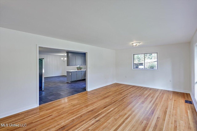 spare room featuring an inviting chandelier and hardwood / wood-style flooring