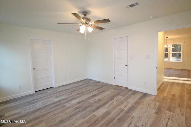 empty room featuring light hardwood / wood-style floors and ceiling fan with notable chandelier