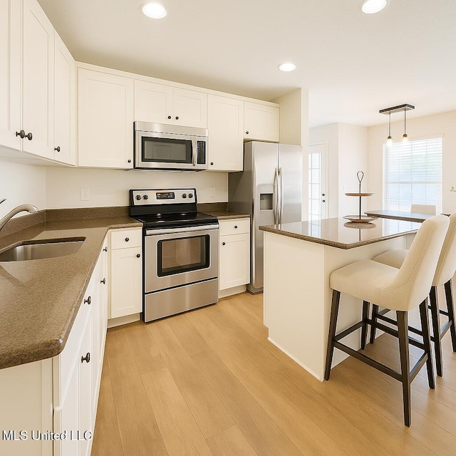 1177 Chestnut Dr, Southaven, MS 38671 - kitchen featuring appliances with stainless steel finishes, light wood-type flooring, a kitchen breakfast bar, white cabinetry, and recessed lighting