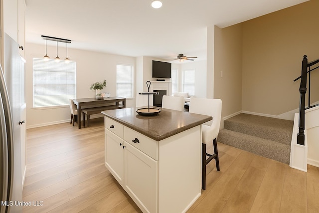 1177 Chestnut Dr, Southaven, MS 38671 - kitchen with dark countertops, a ceiling fan, a center island, a fireplace, and light wood-style flooring