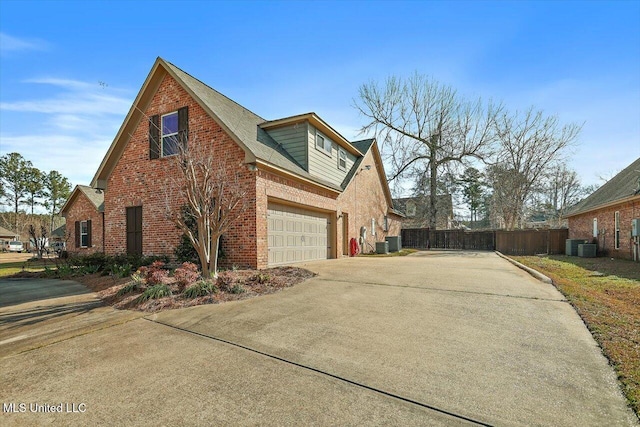 view of property exterior with brick siding, an attached garage, fence, central AC unit, and driveway