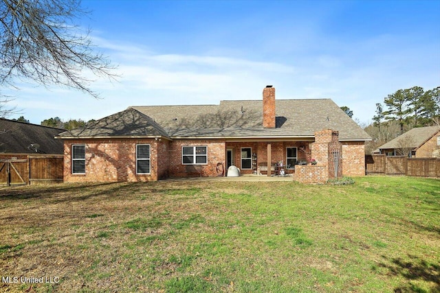 back of house with a patio, a lawn, brick siding, and a fenced backyard