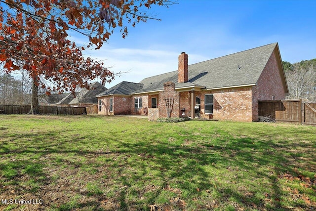 rear view of house featuring a yard, brick siding, a fenced backyard, and a chimney