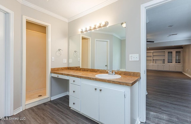 full bathroom with baseboards, vanity, crown molding, wood finished floors, and a shower