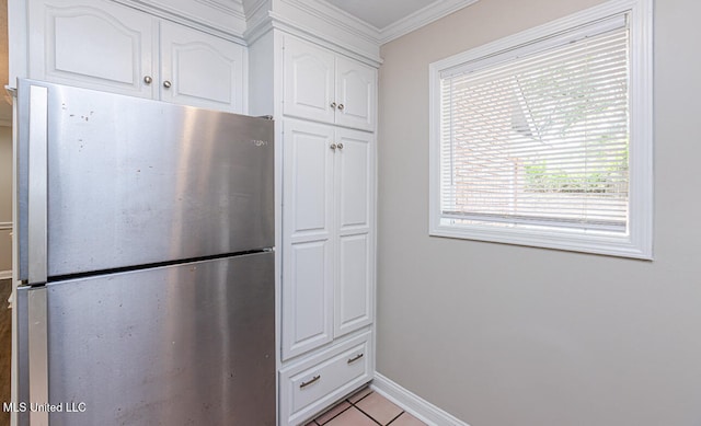 kitchen with crown molding, white cabinetry, light tile patterned flooring, and stainless steel refrigerator