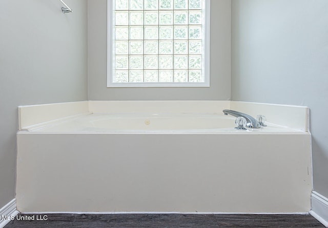 bathroom with a tub to relax in and hardwood / wood-style flooring