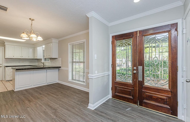 foyer featuring french doors, wood finished floors, ornamental molding, visible vents, and an inviting chandelier