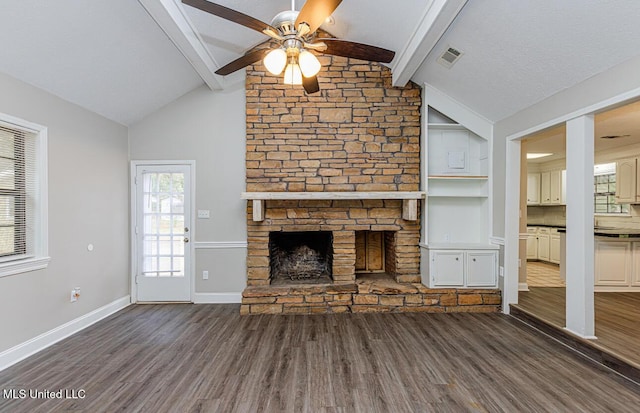 unfurnished living room featuring lofted ceiling with beams, visible vents, dark wood-style flooring, a ceiling fan, and a stone fireplace