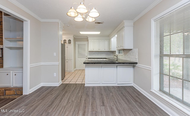 kitchen featuring backsplash, white cabinetry, light wood-type flooring, crown molding, and sink