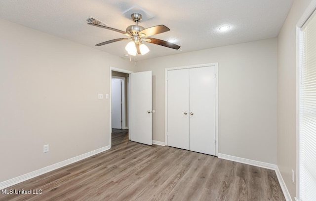 unfurnished bedroom featuring a closet, baseboards, light wood finished floors, ceiling fan, and visible vents