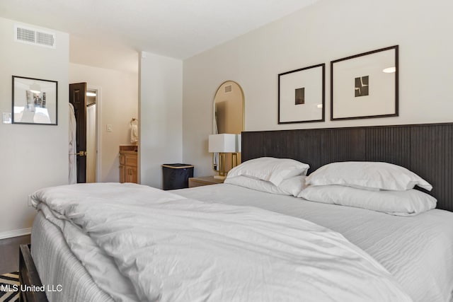 bedroom with arched walkways, visible vents, and baseboards