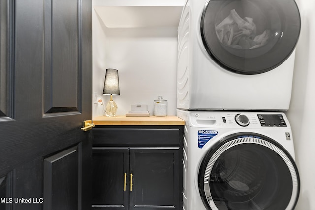 clothes washing area featuring stacked washer and clothes dryer and cabinet space