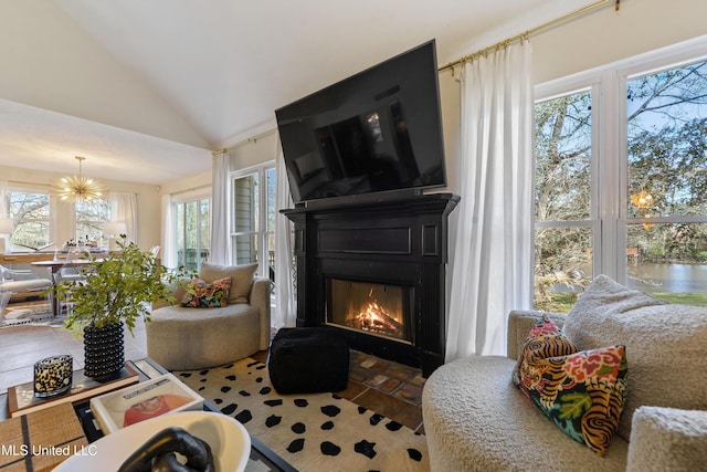 sitting room with vaulted ceiling, a large fireplace, and an inviting chandelier