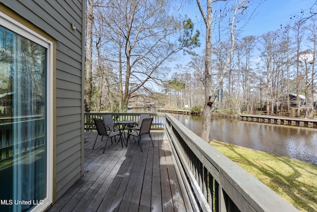 wooden terrace featuring outdoor dining space and a water view