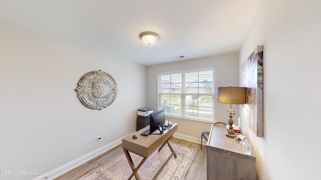 home office with light hardwood / wood-style flooring