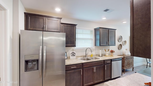 kitchen featuring appliances with stainless steel finishes, dark brown cabinetry, and sink