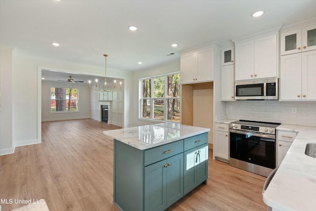 kitchen featuring pendant lighting, stainless steel appliances, white cabinetry, and ceiling fan