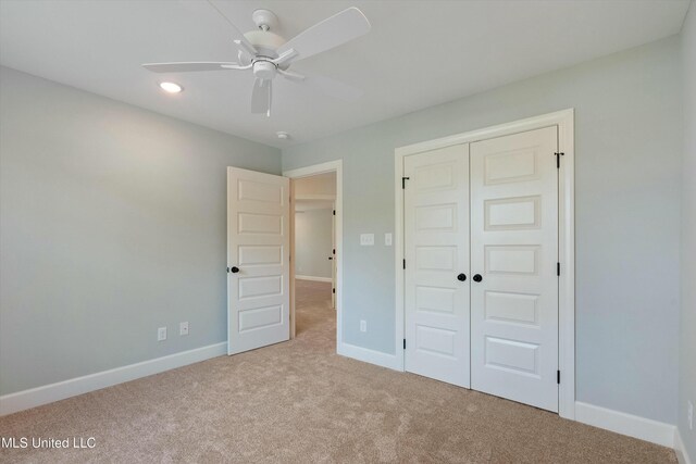 unfurnished bedroom featuring ceiling fan, a closet, and light colored carpet